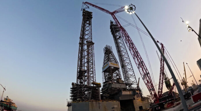Mammoet's CC 8800-1 crawler crane in Boom Booster configuration installing rig leg extension sections at Drydocks World Dubai.